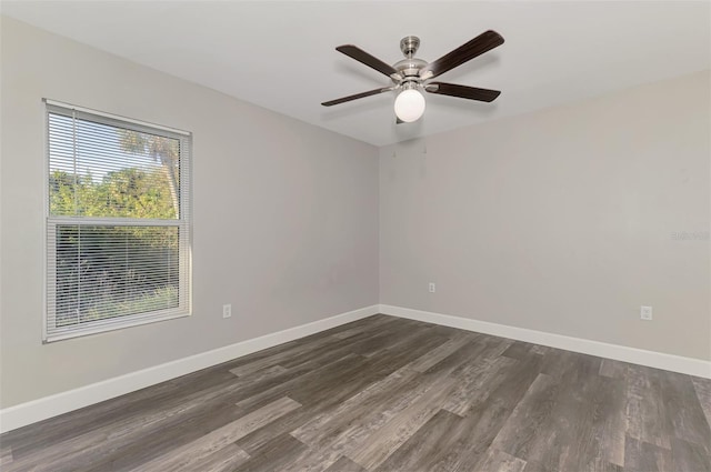 empty room featuring dark wood-type flooring, a ceiling fan, and baseboards