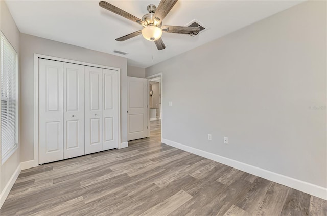 unfurnished bedroom featuring light wood-type flooring, baseboards, a closet, and visible vents