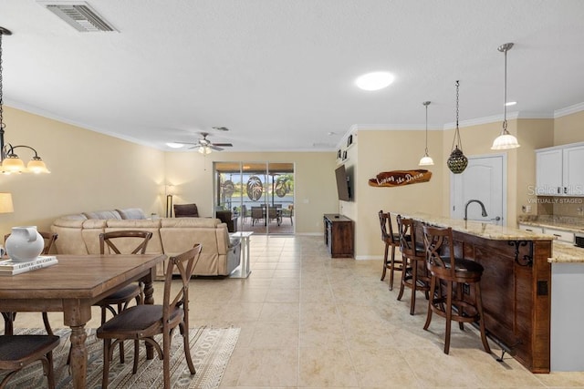 dining room featuring visible vents, crown molding, light tile patterned floors, baseboards, and ceiling fan