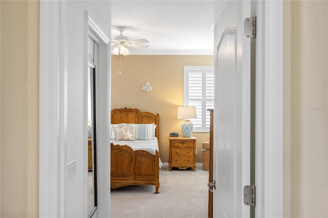 carpeted bedroom featuring a ceiling fan and ornamental molding