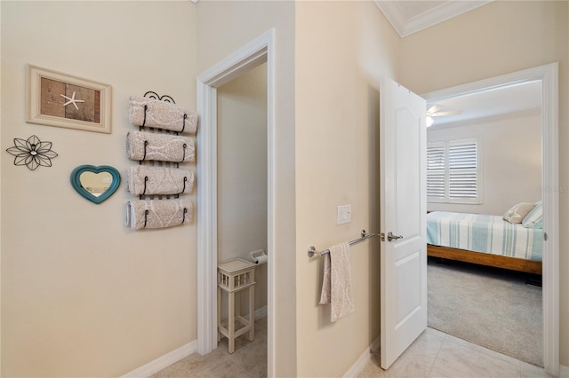 corridor with baseboards, light carpet, ornamental molding, and light tile patterned flooring