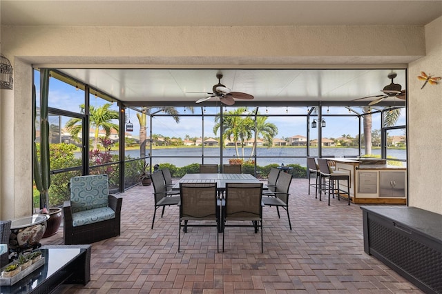 sunroom / solarium featuring a water view, plenty of natural light, and a ceiling fan