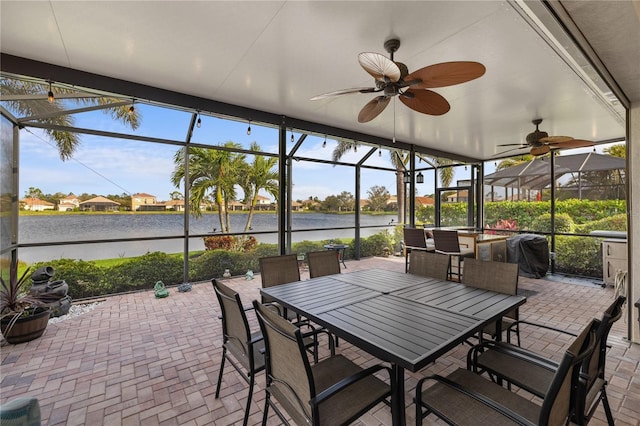 sunroom / solarium featuring a water view, plenty of natural light, and ceiling fan