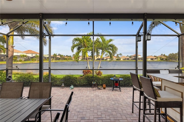 view of patio featuring a lanai, a water view, and outdoor dry bar