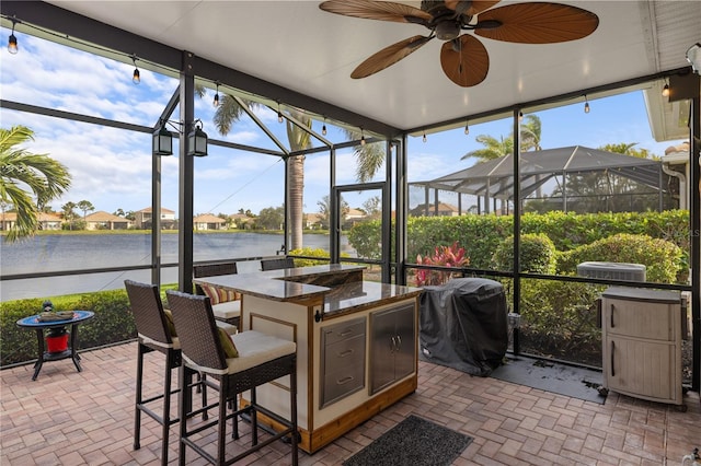 sunroom featuring a wealth of natural light, a water view, and ceiling fan