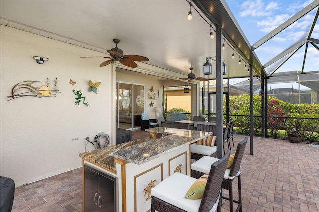 view of patio / terrace featuring outdoor dining space, glass enclosure, and ceiling fan