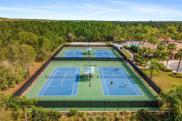 view of tennis court with a view of trees and fence