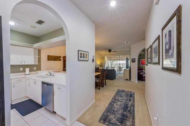 hall with baseboards, visible vents, arched walkways, a sink, and light colored carpet