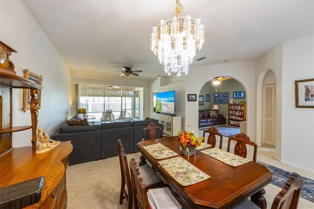 dining space with visible vents, arched walkways, light colored carpet, and ceiling fan with notable chandelier