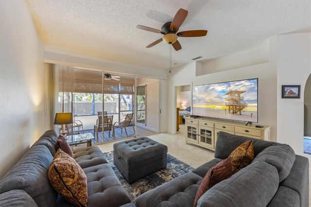 living room with a textured ceiling, ceiling fan, visible vents, and light carpet