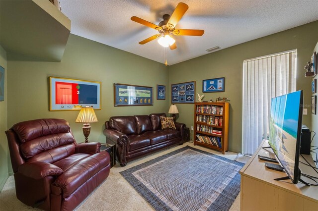 carpeted living room featuring a ceiling fan, visible vents, and a textured ceiling