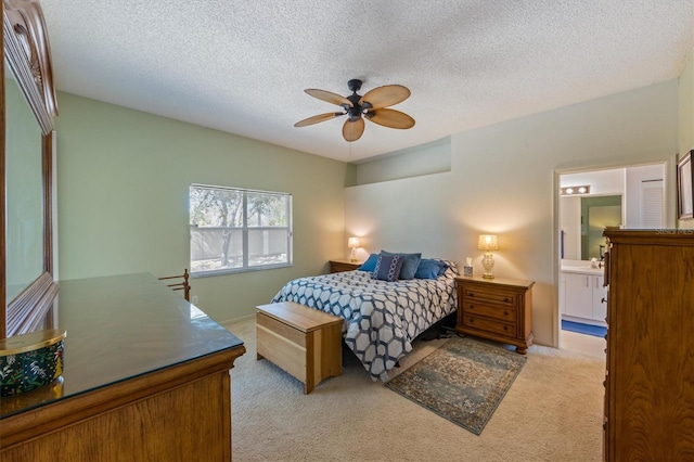 bedroom with light carpet, a textured ceiling, ensuite bath, and a ceiling fan