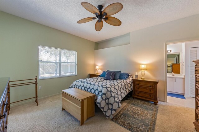 bedroom featuring a textured ceiling, a ceiling fan, baseboards, ensuite bathroom, and light carpet