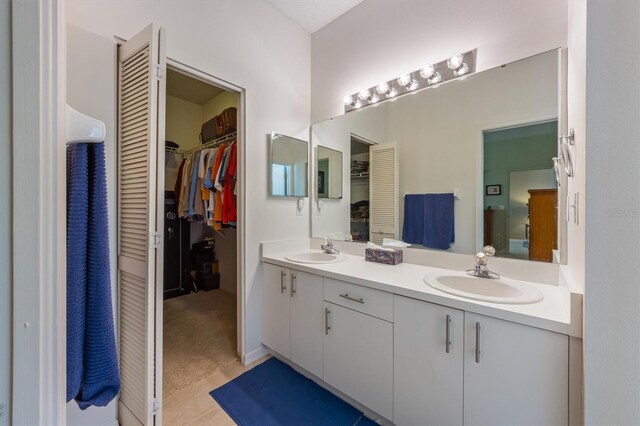 full bath featuring a sink, a walk in closet, and double vanity