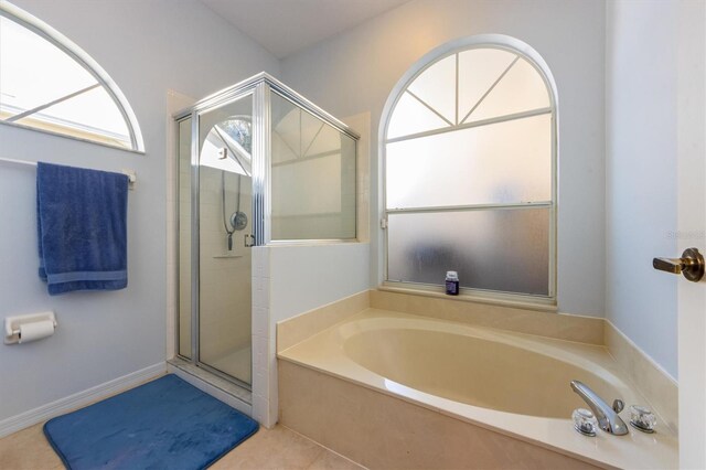 bathroom featuring a bath, tile patterned flooring, and a shower stall