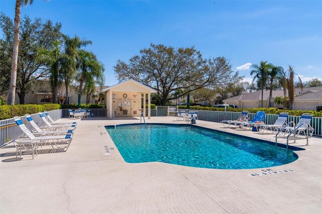 community pool with a patio and fence