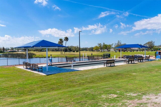 dock area featuring a water view, a lawn, and fence