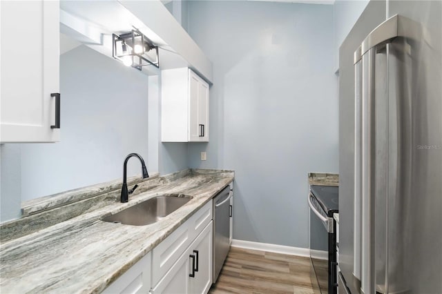 kitchen featuring a sink, stainless steel appliances, light stone countertops, and white cabinetry