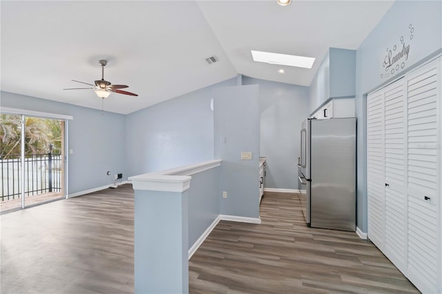 kitchen featuring wood finished floors, visible vents, baseboards, vaulted ceiling with skylight, and freestanding refrigerator