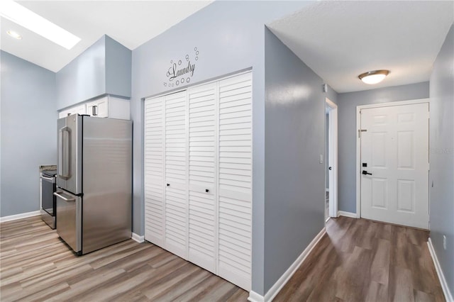 kitchen featuring white cabinetry, light wood-style flooring, baseboards, and freestanding refrigerator