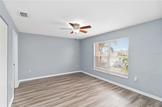 spare room with ceiling fan, wood finished floors, visible vents, and baseboards