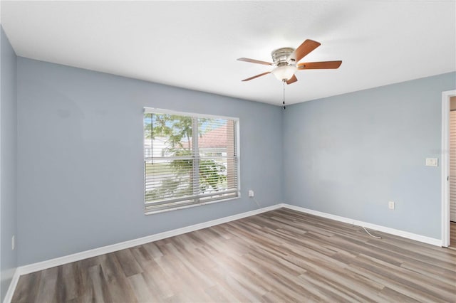 unfurnished room featuring a ceiling fan, wood finished floors, and baseboards