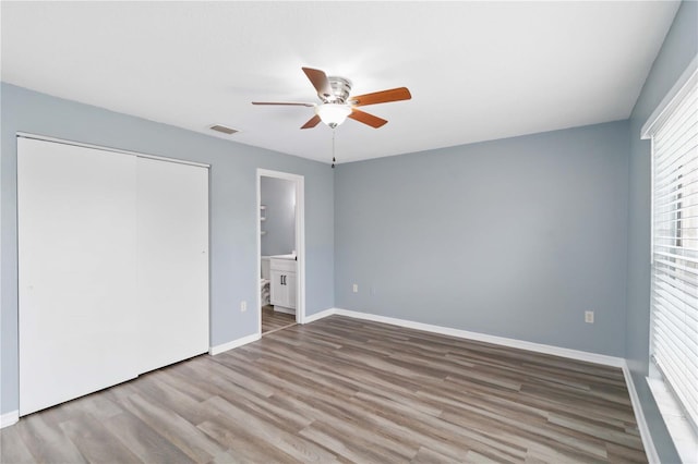 unfurnished bedroom featuring visible vents, baseboards, wood finished floors, a closet, and a ceiling fan