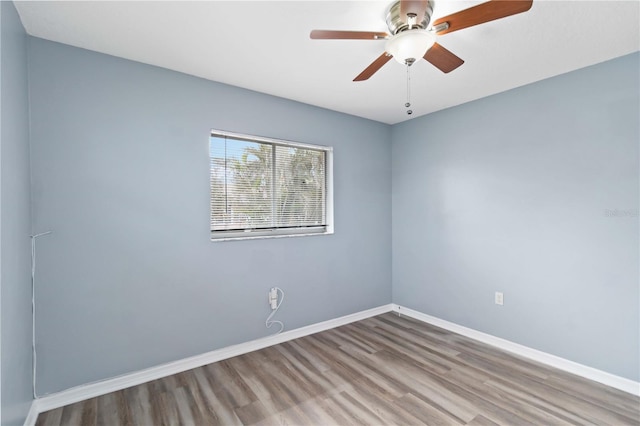 empty room with baseboards, wood finished floors, and a ceiling fan