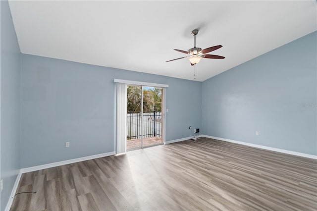 empty room with a ceiling fan, lofted ceiling, wood finished floors, and baseboards