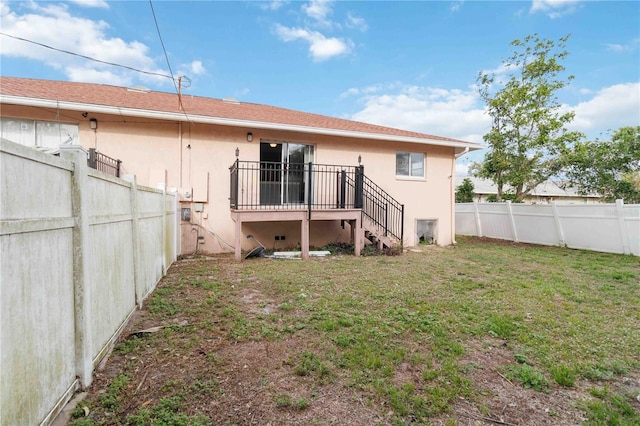 back of property with stucco siding, stairs, a yard, and fence