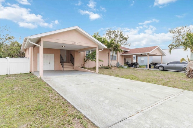 ranch-style house with stucco siding, driveway, fence, a front yard, and a carport