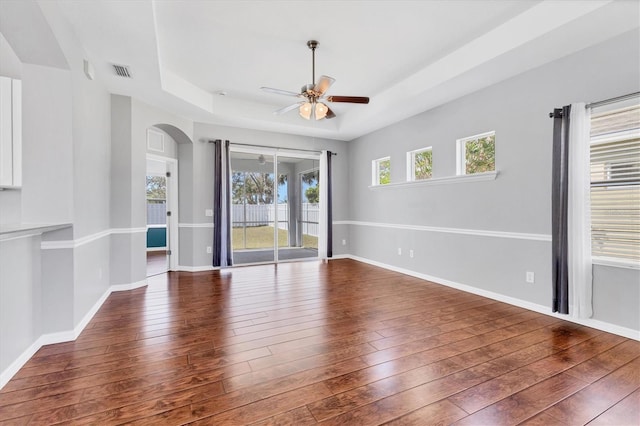 unfurnished room featuring visible vents, a ceiling fan, baseboards, wood-type flooring, and a raised ceiling