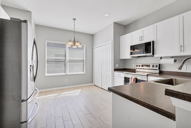 kitchen with dark countertops, appliances with stainless steel finishes, white cabinetry, and a sink