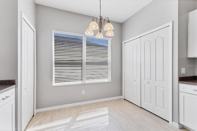 unfurnished dining area with a notable chandelier and baseboards