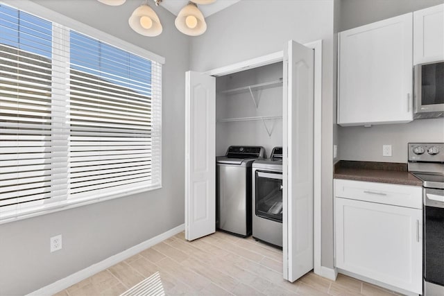 kitchen with baseboards, white cabinetry, stainless steel appliances, washer and dryer, and dark countertops