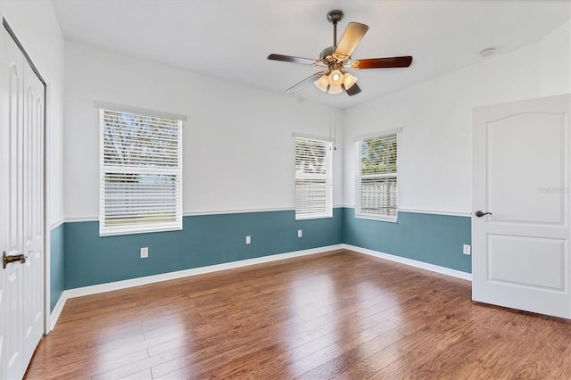 unfurnished room with wood finished floors, baseboards, and ceiling fan