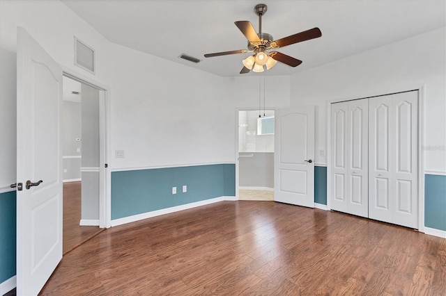 unfurnished bedroom featuring a ceiling fan, wood finished floors, visible vents, and baseboards