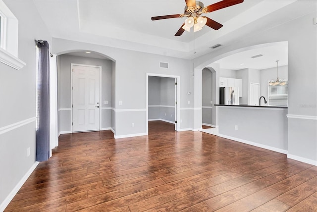 unfurnished living room with visible vents, a raised ceiling, baseboards, and hardwood / wood-style floors