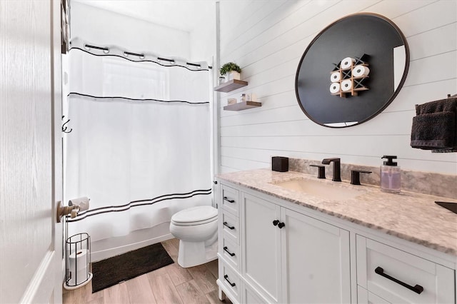 bathroom featuring toilet, vanity, shower / tub combo with curtain, and wood finished floors