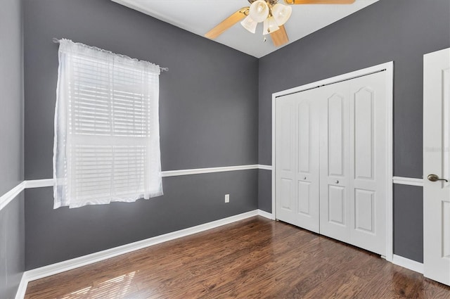 unfurnished bedroom with ceiling fan, a closet, baseboards, and wood finished floors