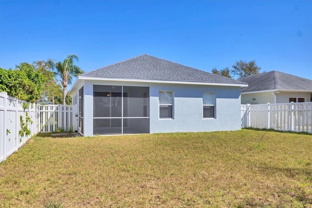 back of property with a fenced backyard, a sunroom, stucco siding, a shingled roof, and a lawn