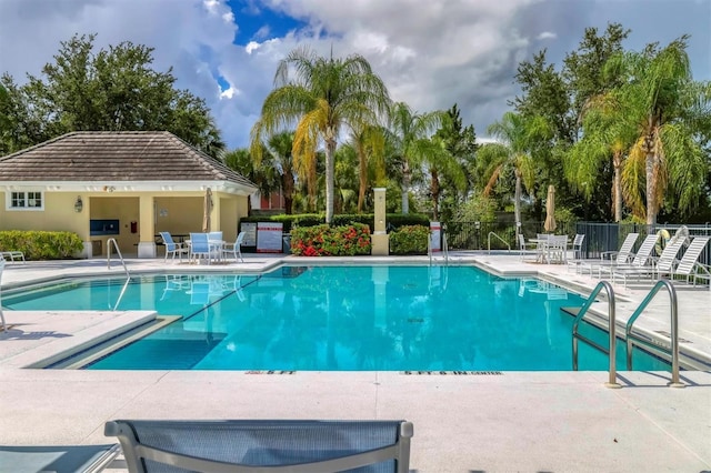 community pool with a patio area and fence