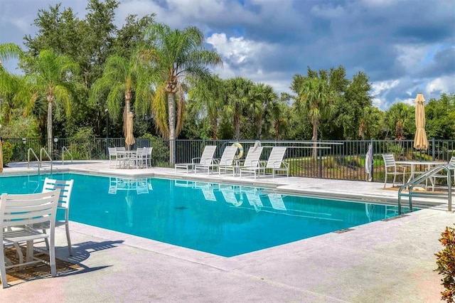 community pool with a patio area and fence