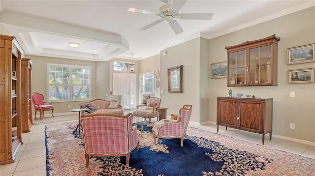 living area with light tile patterned floors, baseboards, crown molding, and a tray ceiling