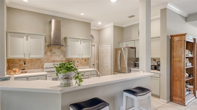 kitchen featuring white electric range oven, visible vents, freestanding refrigerator, ornamental molding, and wall chimney range hood