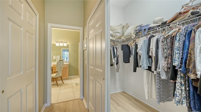 walk in closet with light wood finished floors