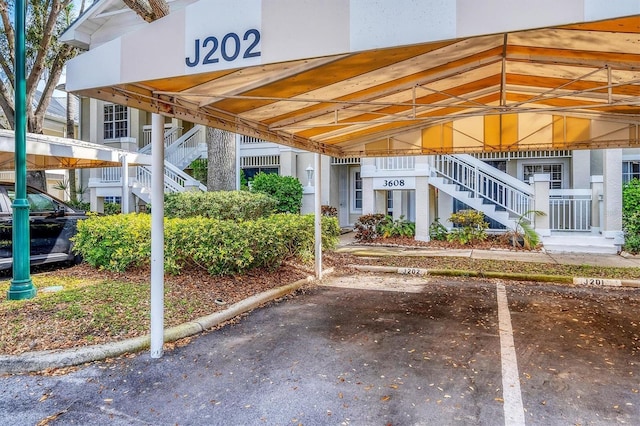 view of property featuring covered parking and stairs