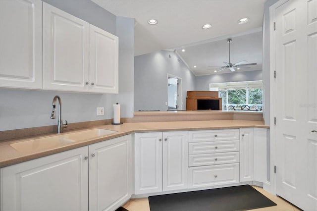 kitchen featuring light countertops, white cabinets, a ceiling fan, and a sink