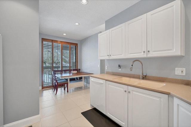 kitchen with a sink, dishwasher, light countertops, and white cabinetry