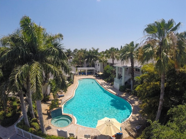 pool with a patio area, a hot tub, and fence